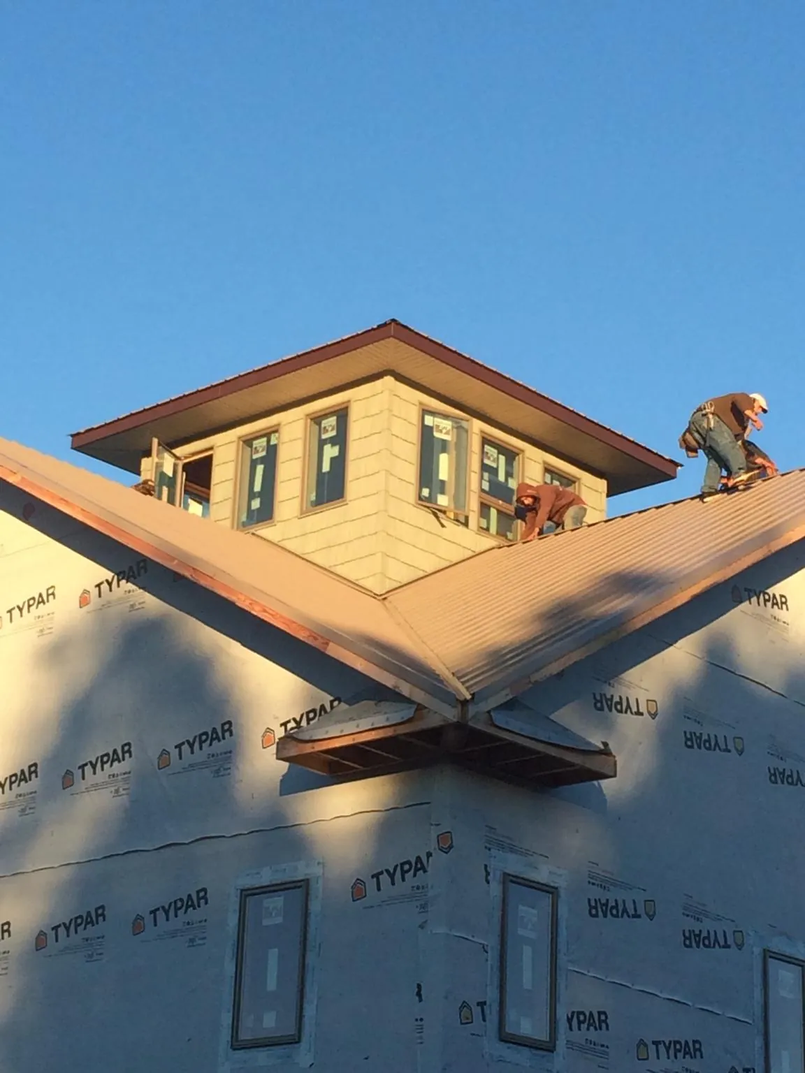 Roofers working around a rooftop cupola on a new metal roof at sunset — Roof Waterproofing in Edenton by Roofing Brothers
